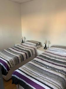 two beds in a room with two lamps at The Carisbrooke in Forres