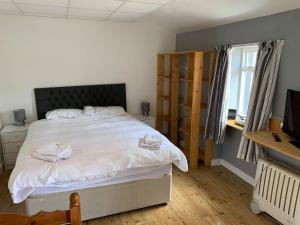 Cette chambre comprend un lit avec des draps blancs et une télévision. dans l'établissement The Carisbrooke, à Forres