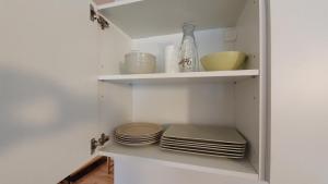 a white kitchen with plates and bowls on shelves at Littlepanther Balaton in Balatonföldvár