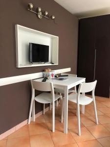 een witte eettafel met 2 stoelen en een tv bij Appartamento Bomboniera in Rovigo