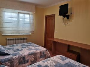 1 dormitorio con 2 camas y TV en la pared en Apartamento próximo a Playa Llas, en Foz