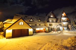 ポロニンにあるApartamenty Willa Annaの夜間の雪の中のガレージ付き家