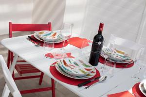 un tavolo bianco con piatti rossi e bianchi e una bottiglia di vino di Coral Holiday San Vito Lo Capo a San Vito lo Capo