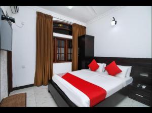 a bedroom with a large bed with red pillows at OYO MotelVIP in Colombo