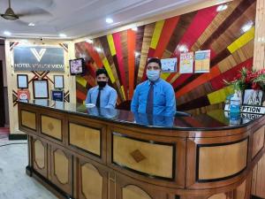 two people wearing masks standing behind a counter at Hotel Valley View in Mandi
