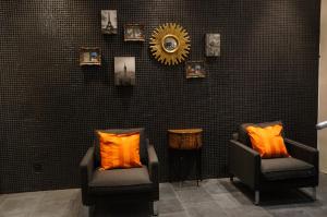 two chairs with orange pillows and a mirror on a wall at Hotel Aviation in Brussels