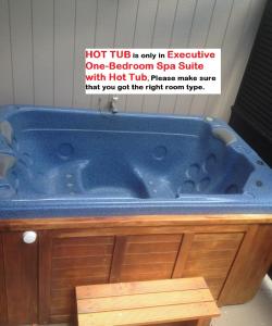 a blue tub in a bathroom with a sign on it at Executive On Fenton in Rotorua