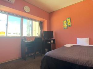 Schlafzimmer mit einem Bett, einem Schreibtisch und einem Fenster in der Unterkunft Time Rich in Okinawa