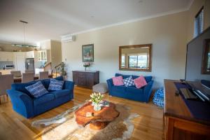 ein Wohnzimmer mit 2 blauen Sofas und einem Tisch in der Unterkunft Paula's Place 8 Ti Tree Close Robe in Robe