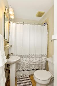 La salle de bains est pourvue d'un rideau de douche blanc et de toilettes. dans l'établissement North End Cottage, à Boise 16 autres photos