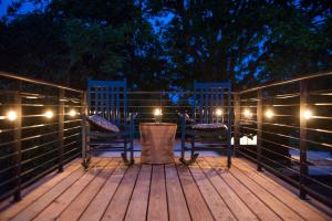 a deck with two chairs and lights at night at The Woods- Container Tiny House 12 min to Magnolia/Baylor/Downtown in Bellmead