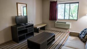 a small living room with a couch and a tv at Super 8 by Wyndham Groton in Groton