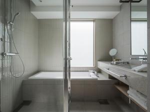 a bathroom with a shower and a tub and a sink at Zentis Osaka in Osaka