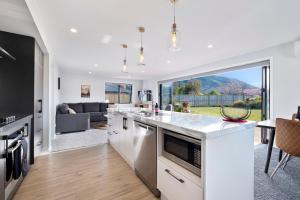 a kitchen and living room with a large window at Paradise Found - Lake Hawea Holiday Home in Lake Hāwea