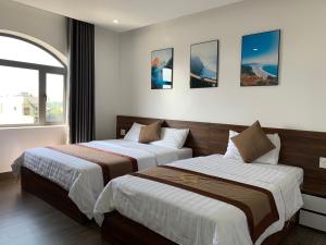 two beds in a hotel room with a window at Win Win Hotel - Khách Sạn Hải Phòng in Hai Phong