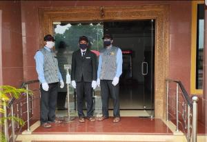 a group of three men wearing masks standing on a porch at Hotel Sharada International in Udupi