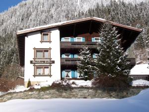 a building in the snow with a tree in front of it at Gästehaus Sahler in Gaschurn