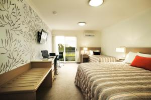 a hotel room with two beds and a desk at Loxton Community Hotel Motel in Loxton