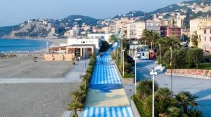 een pad met blauwe en witte parasols op een strand bij A due passi dal mare appartamento con giardino in Albissola Marina