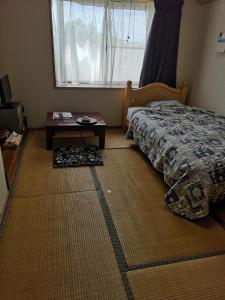 een slaapkamer met een bed, een tafel en een raam bij Nanauraso in Sado