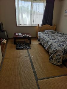 a bedroom with a bed and a table and a window at Nanauraso in Sado