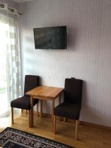 a wooden table with two chairs and a television on a wall at U Pauli i Eryka in Łeba