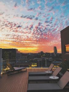Alex Perry Hotel & Apartments في بريزبين: غروب الشمس على سطح مبنى مع مقاعد