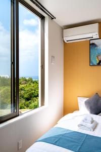 a bedroom with a bed and a large window at Ocean Villa Fuchaku Okinawa in Fuzuchi