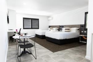 a bedroom with two beds and a table and a desk at Fountain View Motel in Dubbo
