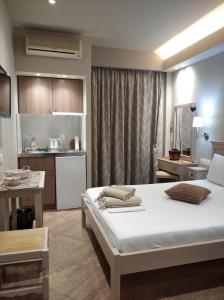 a bedroom with a large bed and a kitchen at Maltezos Rooms in Methana