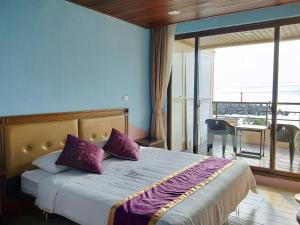 a bedroom with a bed with purple pillows and a balcony at Two Fish Homestay in Lanyu