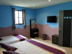 a bedroom with two beds and a flat screen tv at Two Fish Homestay in Lanyu