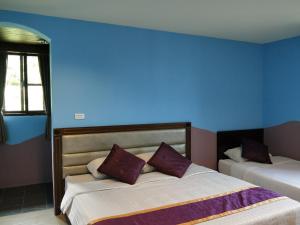a bedroom with two beds and a blue wall at Two Fish Homestay in Lanyu
