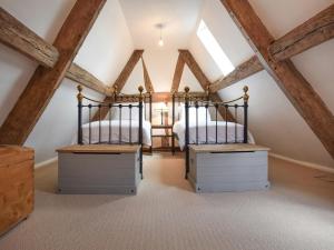 2 bedden in een zolderslaapkamer met houten balken bij Mercia House in Winchcombe