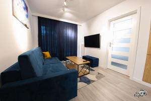 a living room with a blue couch and a table at Apartamenty RÓŻA WIATRÓW - MARINA BORKI in Augustów