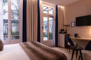 a hotel room with a bed and a desk and windows at Lord Byron in Paris