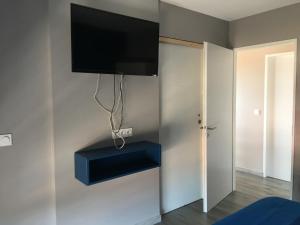a flat screen tv hanging on a wall with a blue shelf at Fun and sun room in Salles-d'Aude