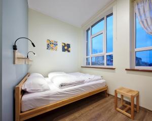 a bed in a room with two windows at DREAM Hostel Khmelnytskyi in Khmelnytskyi