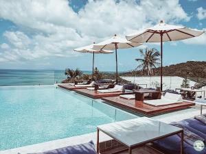 ein Swimmingpool mit Stühlen und Sonnenschirmen und das Meer in der Unterkunft High Life Villas in Salad Beach