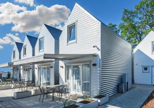 Biały dom z niebieskim dachem i patio w obiekcie Na Klifie Wypoczynek&Spa w Rewalu