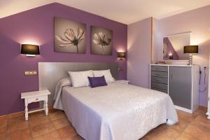 1 dormitorio con paredes moradas y 1 cama blanca en Apartamentos Cinca, en Escalona