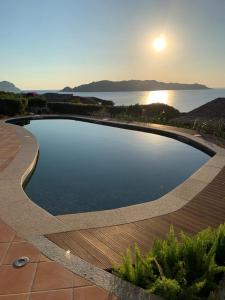 una piscina con puesta de sol en el fondo en Villa Caterina, en Monte Petrosu