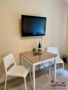 mesa de comedor con 2 sillas y TV en la pared en estrella24 LIVING ROOMS 87 Paris, en Herne