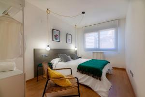a bedroom with a bed and a chair and a window at Apartamentos Turísticos Rioja y Camino in Huércanos +11 photos