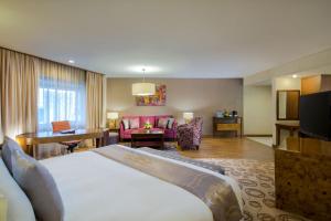 ein Hotelzimmer mit einem Bett und einem Wohnzimmer in der Unterkunft Grand Sahid Jaya CBD in Jakarta
