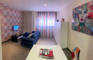 a living room with a blue couch and a painting at Estudio con piscina y Wifi in Ciudad Real