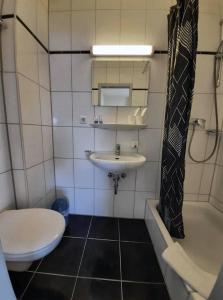 a bathroom with a toilet and a sink and a tub at Traube Hotel Oeffingen in Fellbach