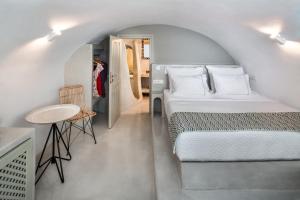 um quarto com uma cama e uma pequena mesa e cadeira em Kaleidoscope Oia Suites em Oia