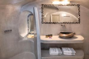 a bathroom with a sink and a mirror at Kaleidoscope Oia Suites in Oia