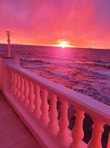 a sunset over the ocean with a white railing at Hotel Ariana in Marine du Miomo